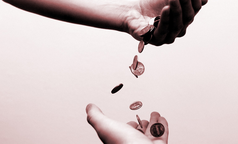 Coins falling between two hands.