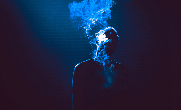 Shawdowed figure blowing smoke
