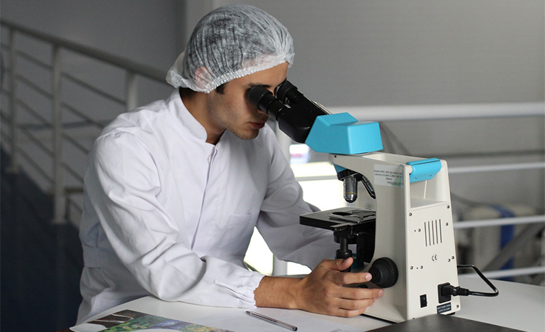 Man in a lab looking through a microscope