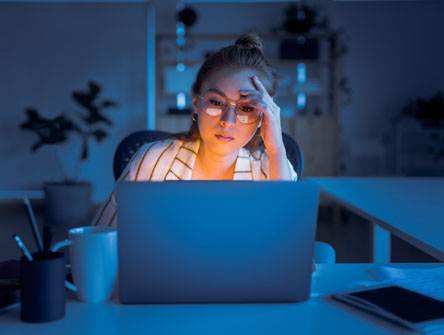Tired woman at a keyboard in the dark.