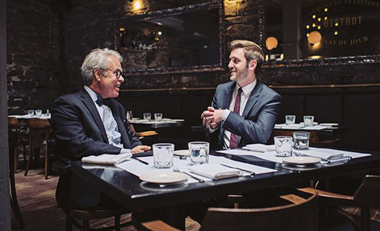 Two men are seated together for a light meal at Modavie in Old Montréal