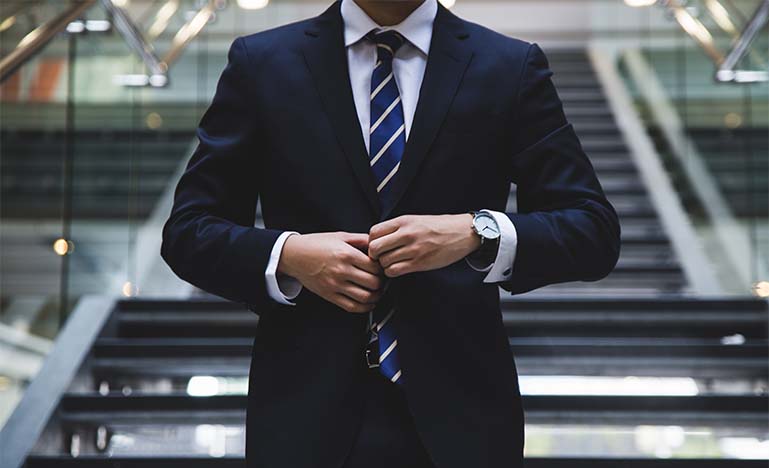 Man buttoning up suit jacket in front of stairs