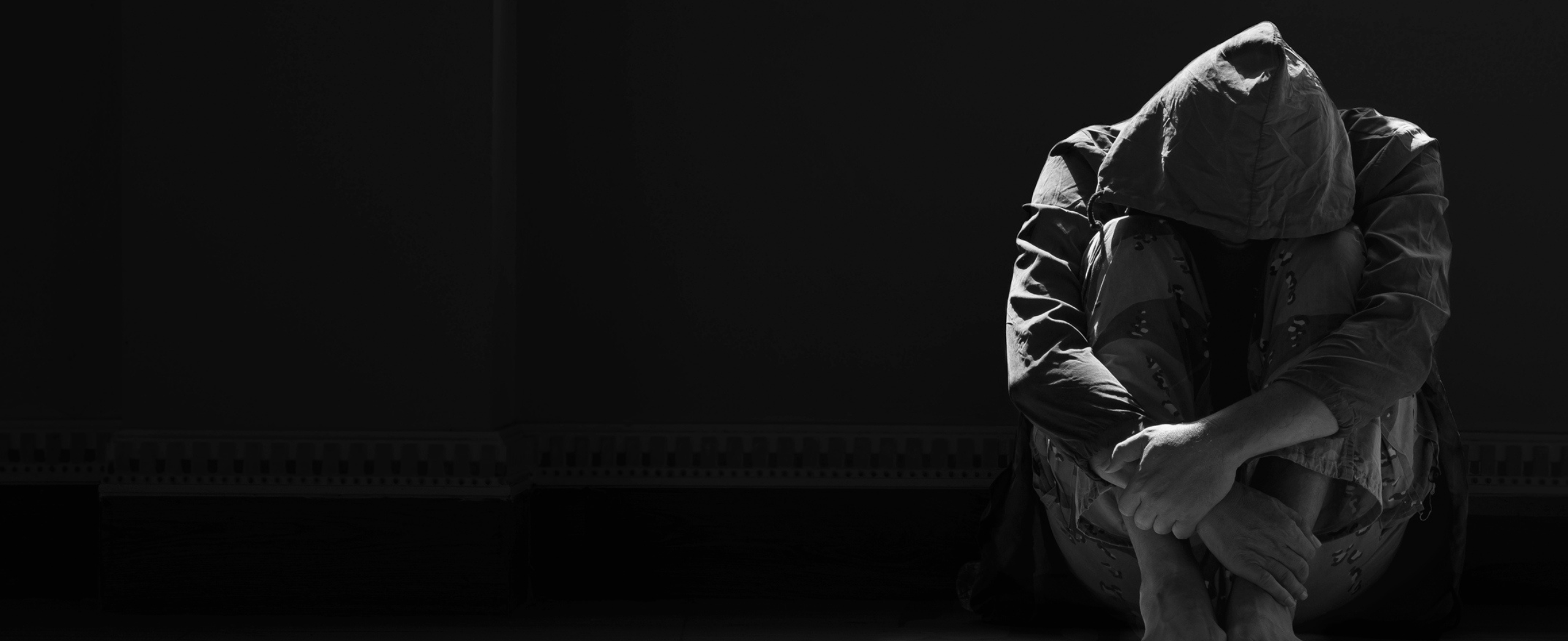 Une personne est accroupie seule dans l'obscurité.