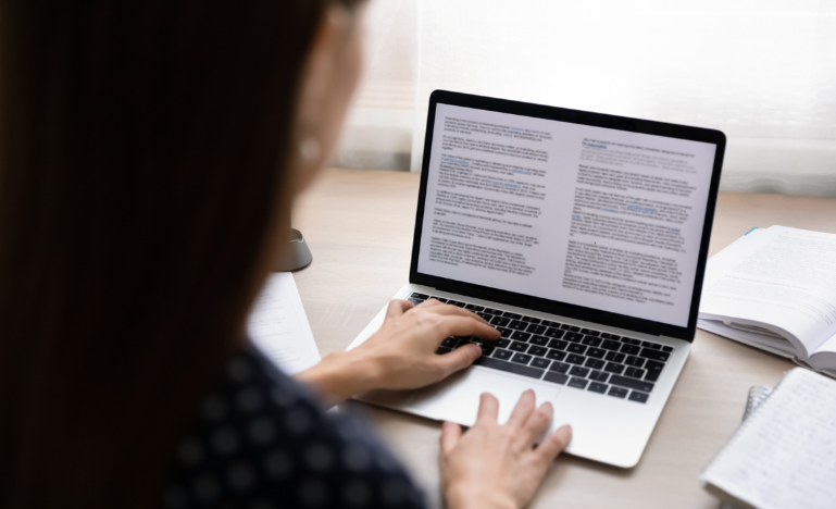 A woman writes a letter on a computer