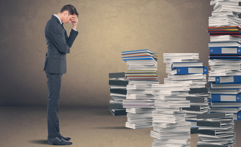 A lawyer looks at a large pile of research materials stacked on the floor