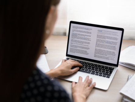 A woman writes a letter on a computer