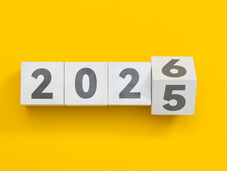 Bloc de cube en bois changeant de 2025 à 2026 sur fond jaune