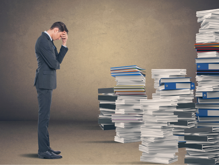 A lawyer looks at a large pile of research materials stacked on the floor