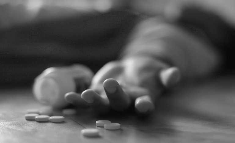 A man lays on the floor, unconscious due to a drug overdose