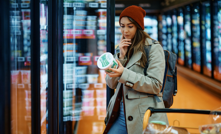 A woman reads a nutrition label while buying dairy product in supermarket