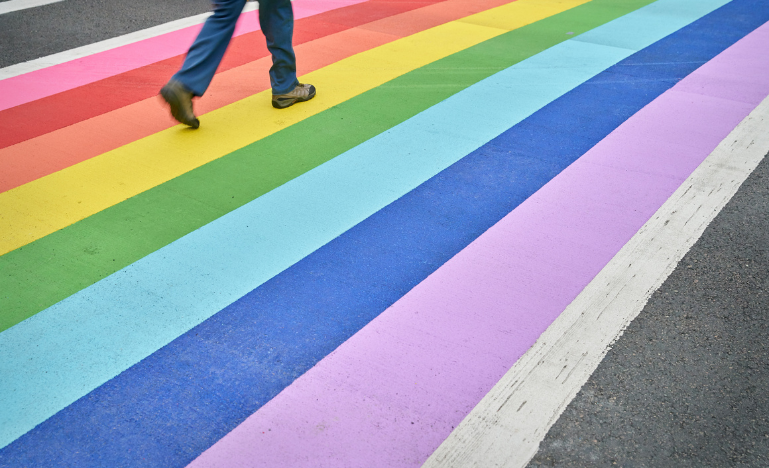 A person walks along a rainbow crosswalk in Vancouver