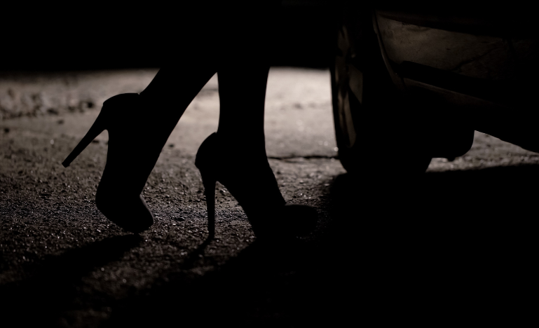 Silhouette of female legs in high heels coming to car