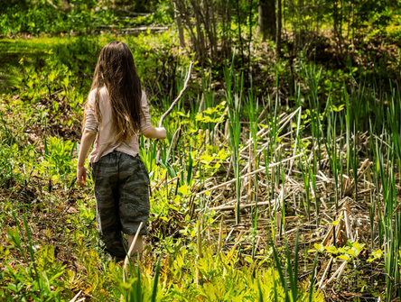A girl walks along a pond