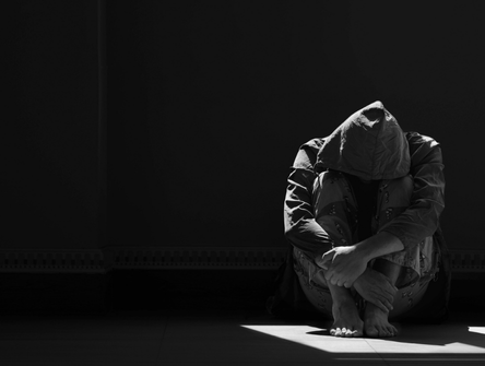 A person crouches alone in the dark