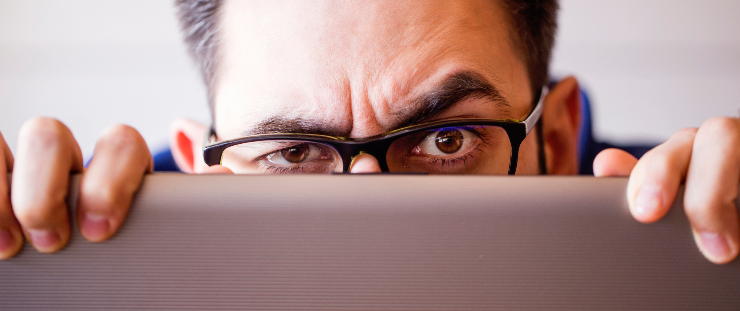A man peeks over the top of laptop computer