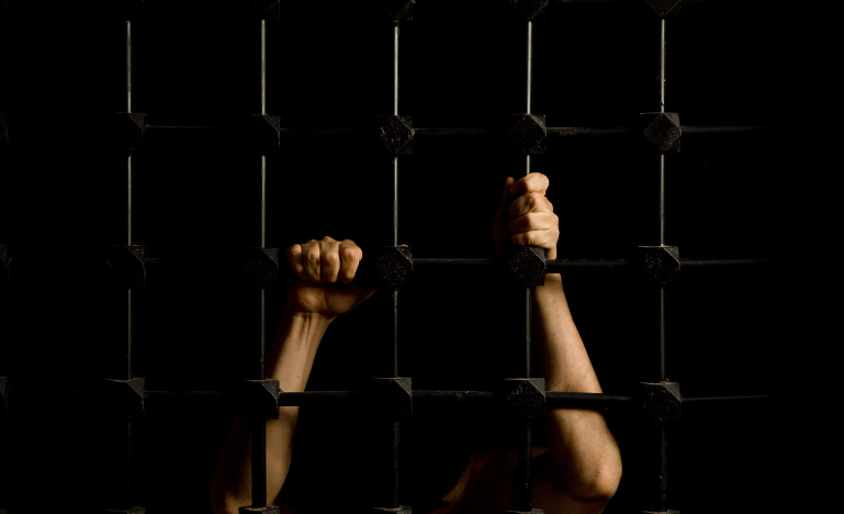 Mains d'un prisonnier à travers les barreaux de la cellule