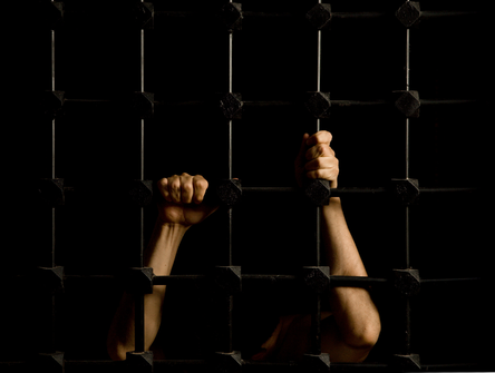 Mains d'un prisonnier à travers les barreaux de la cellule